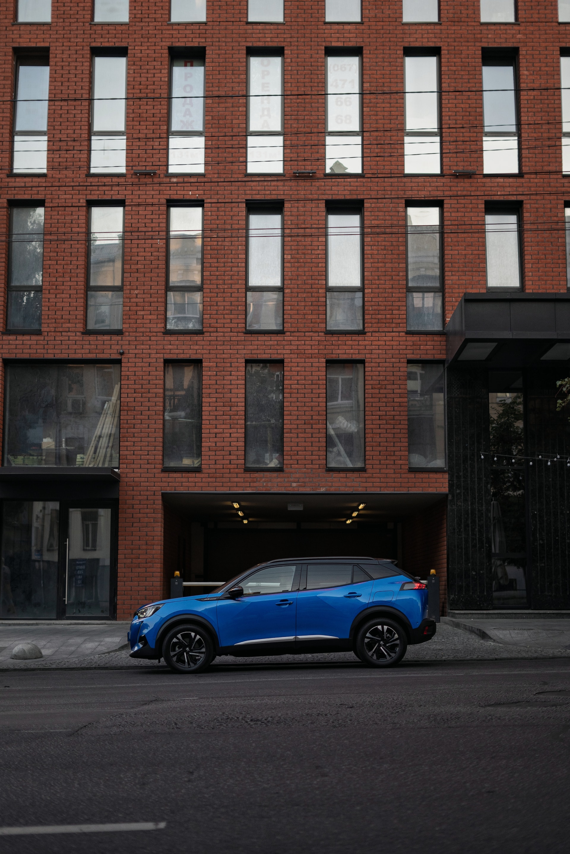 a blue car parked in front of a tall brick building